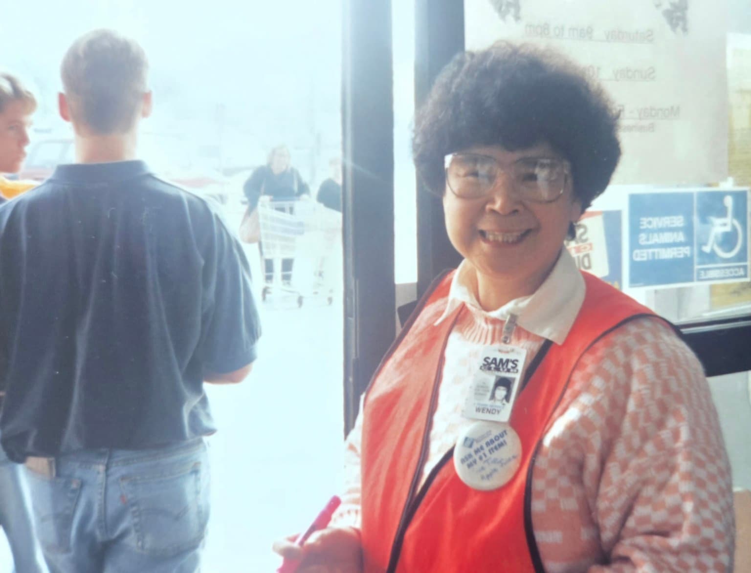 Wendy Ye smiling at a Sam’s Club entrance in her work vest and name badge